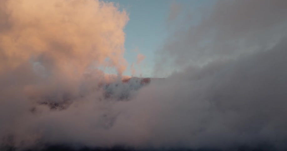 Sunlight tints the part of the clouds floating through the blue sky red