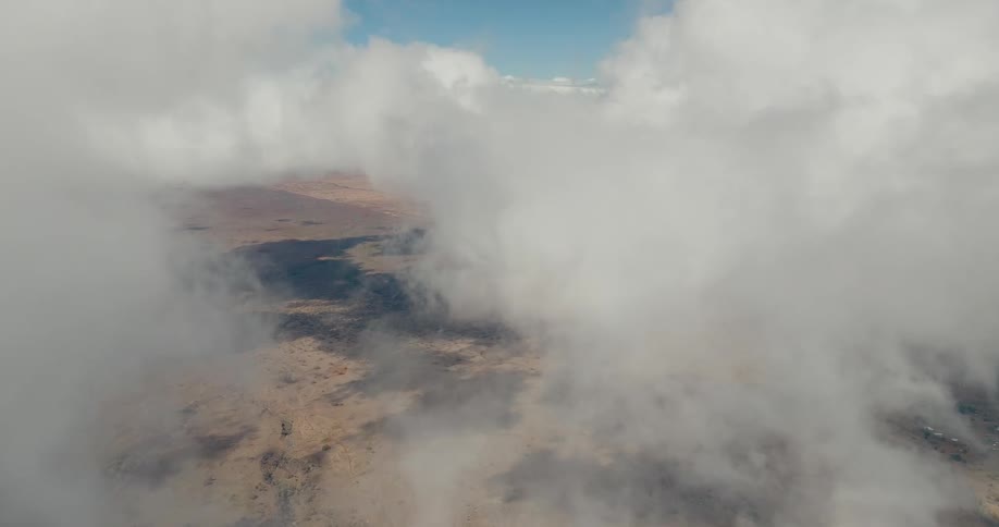 Arid terrain seen from above partially covered by dense clouds