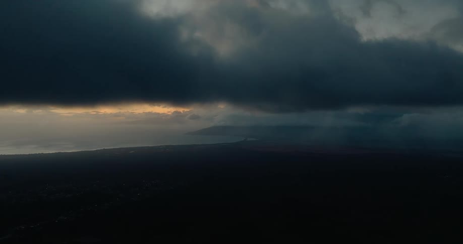 Dense cloud layer moving over a dark landscape with a strip of light on the horizon