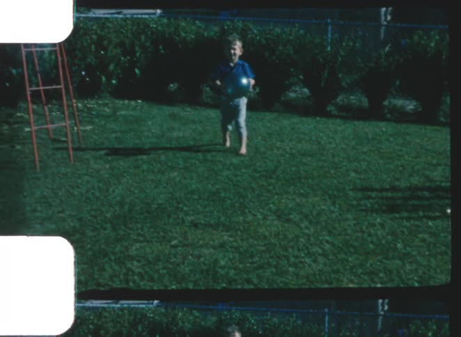 The child is playing with a ball in the yard