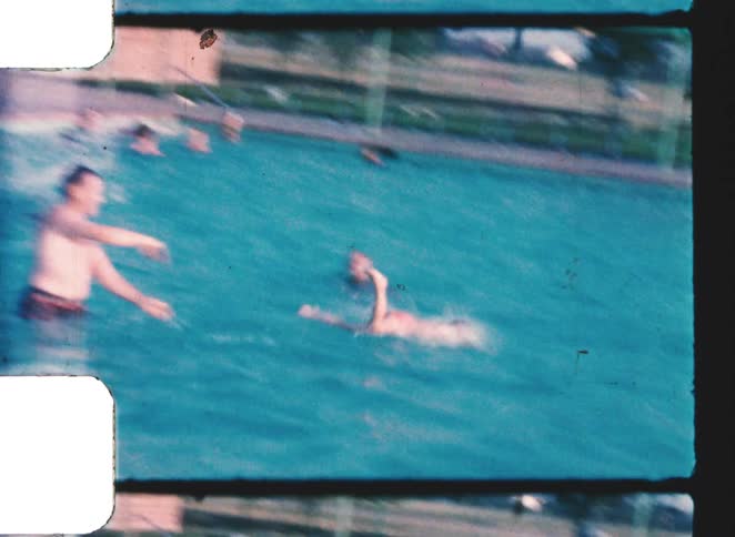 Adult throwing a child into a swimming pool while other people swim nearby