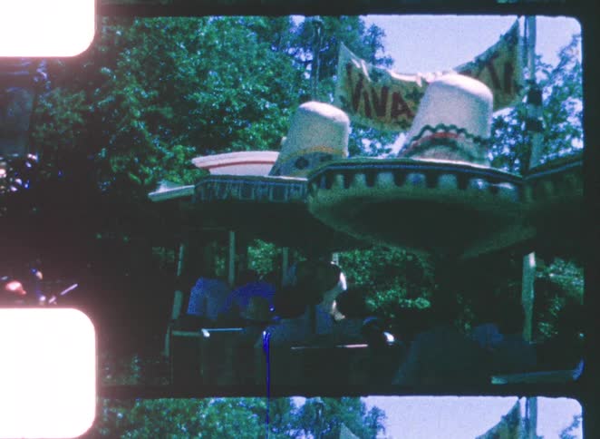 A group of people rides a train through a public park at midday their excitement clear as they enjoy the bright lively atmosphere