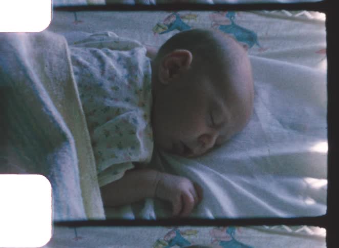 Baby sleeping on their side on a sheet with a partially folded blanket