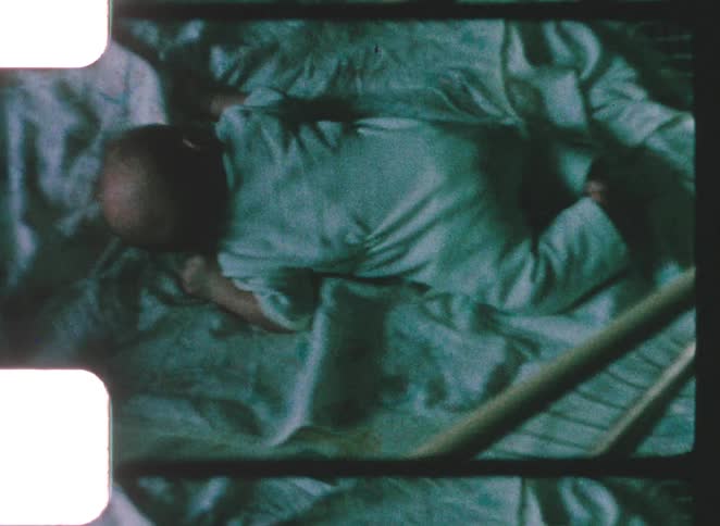 Baby lying face down on a sheet on a padded surface
