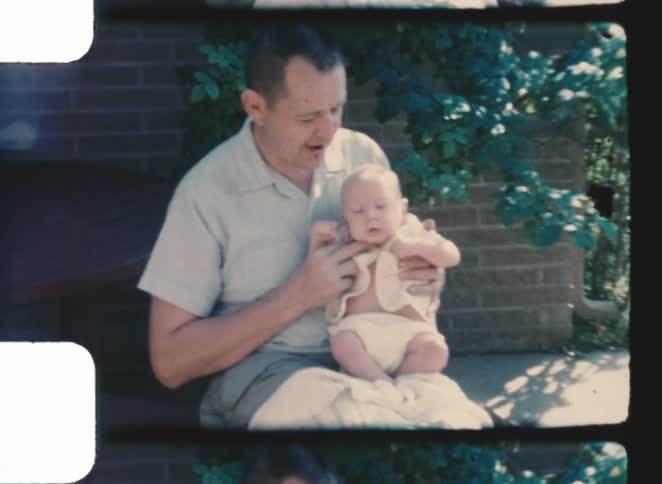 The father holds his baby and smiles