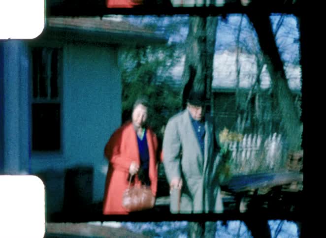 A man and woman walking out of a house