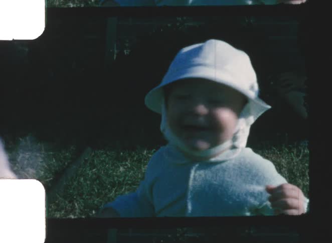The bunny runs past the baby sitting on the grass