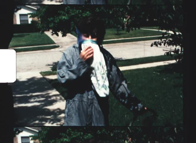 Woman in residential area holding an object while wearing protective clothing