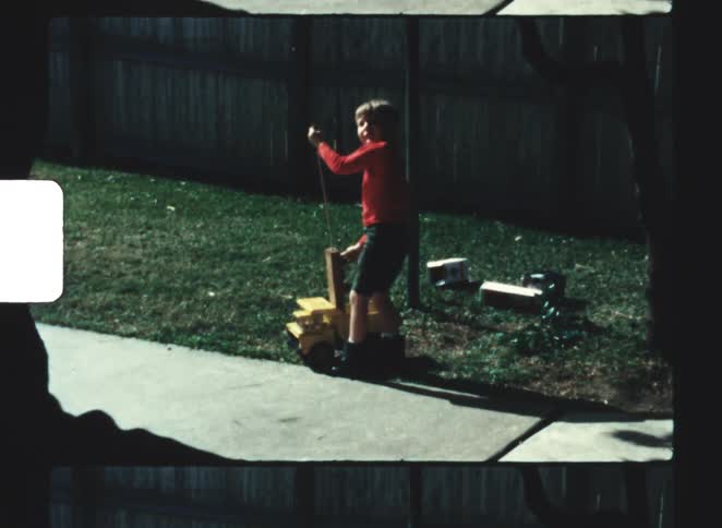 A kid playing with a toy on the sidewalk on a sunny day