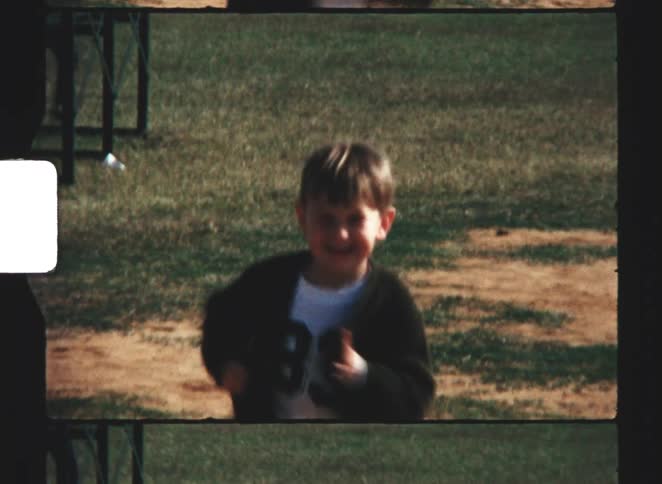 Child running in an open area with dirt ground and surrounding grass
