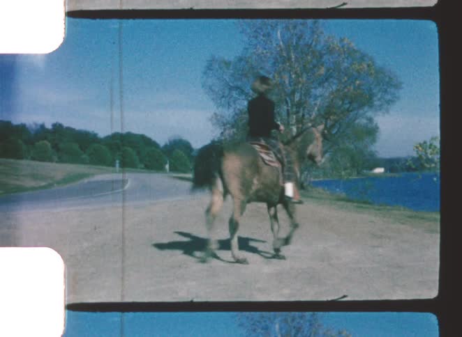 A woman rides her horse across a street