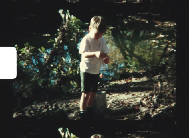 The boy is putting bait on his fishing line