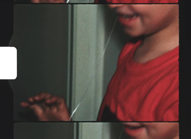 The boy is trying to pull a baby tooth by tying string to a doorknob