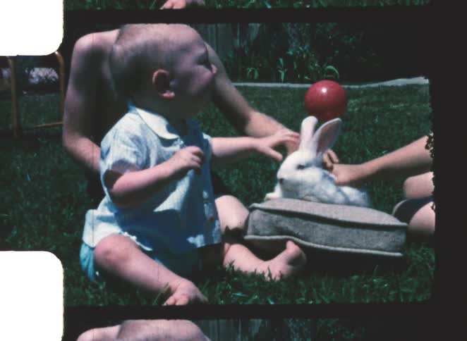 A baby and mother petting a rabbit