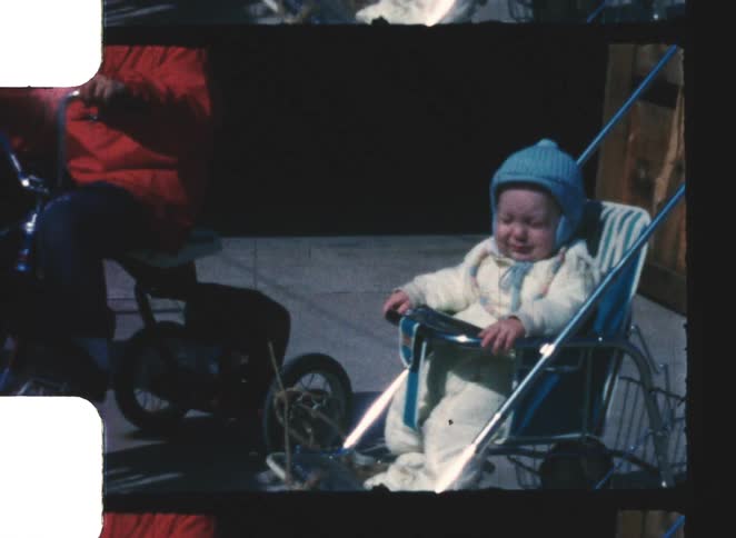 A baby sits in a stroller and a kid sits on a bike