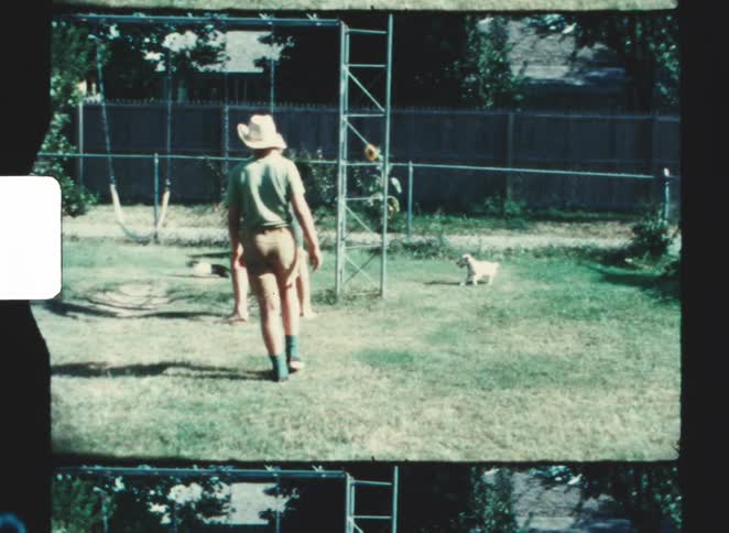 Two teenage boys one chasing a puppy around the backyard on a sunny day