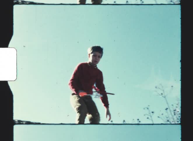 A teenage boy throwing a toy after picking it up from the floor on a sunny day