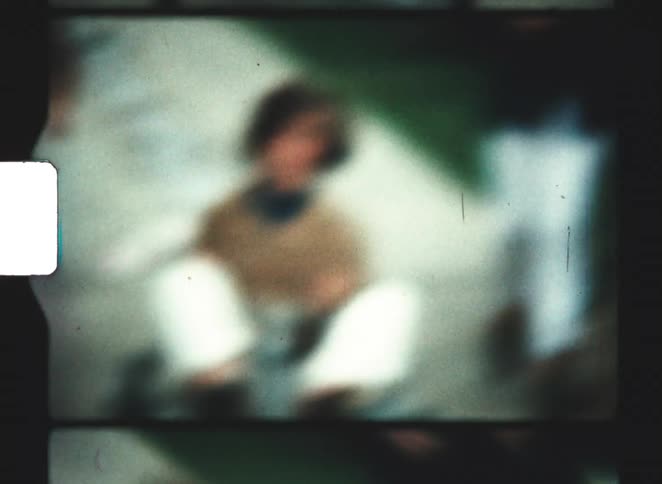 A young woman riding a gokart in the street with a smile on her face as a teenage boy runs toward her to help keep the kart under control at midday