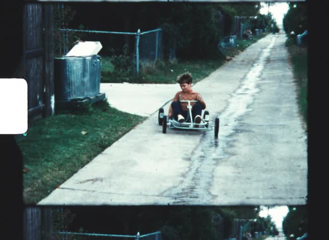 A boy drives a toy kart down the road