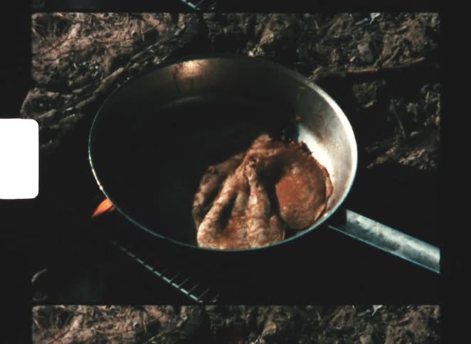 A pan sits over an open fire outside