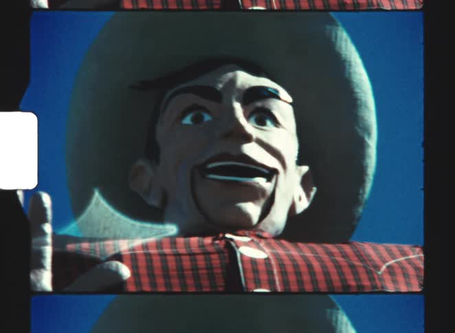 Cowboy statue with widebrimmed hat and red plaid shirt under blue sky