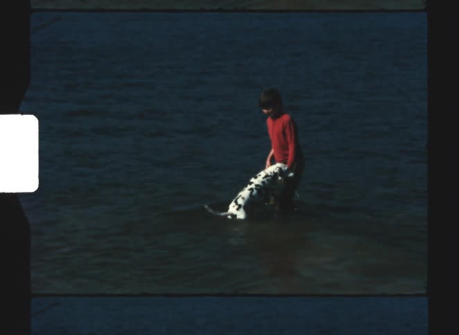 The boy is playing with his dog in the lake water
