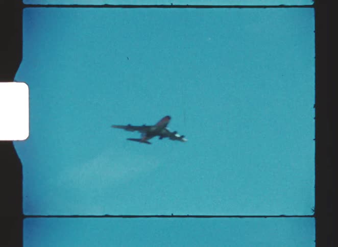 A passenger airplane flies overhead beneath a cloudless blue sky