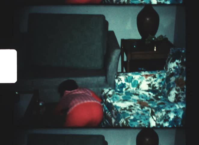 Young boys in pajamas searching candies in a dimly lit living room captured in a vintage 8mm film look