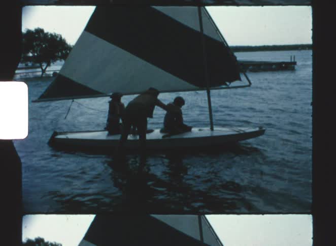 The man helps the child put on a life vest in the boat