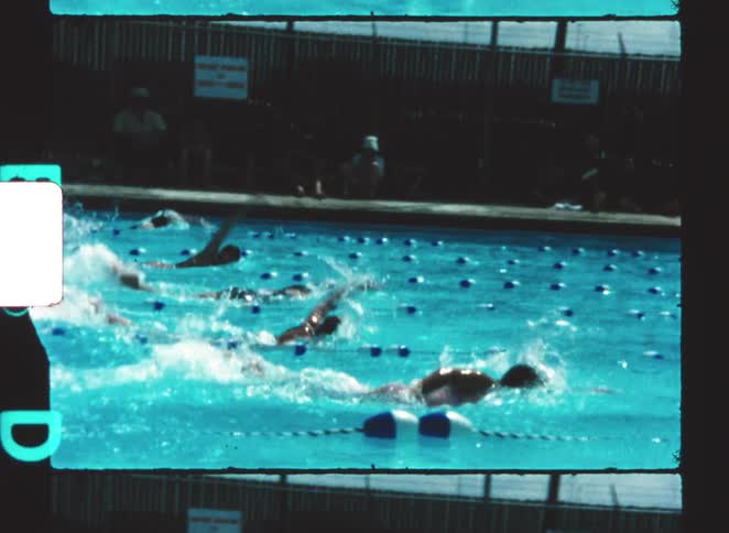 Female athletes compete in an outdoor swimming pool during a swim meet