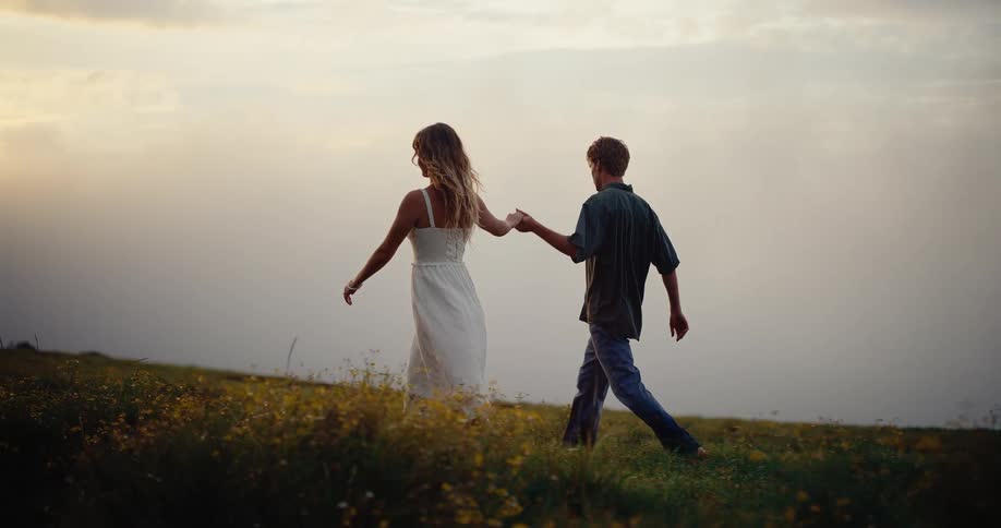A man and woman holding hands walknig outdoors