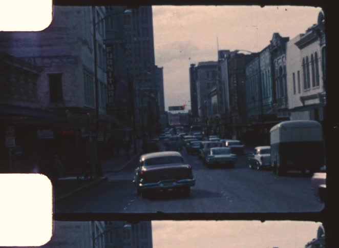 Urban street with commercial buildings and classic cars driving in opposite directions