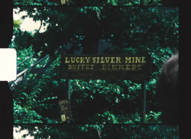 A sign reading lucky silver mine buffet dinner standing in the jungle at midday