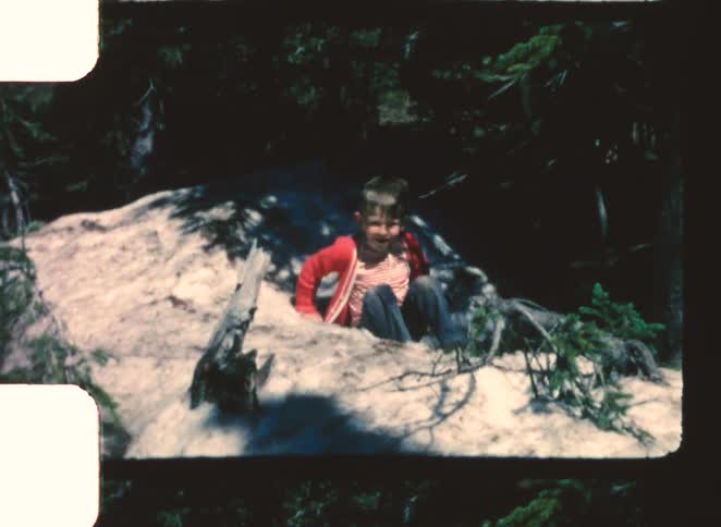 Boy slips on a short slope while walking near the woods during the daytime