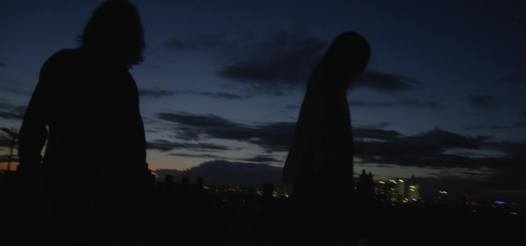 Two people walk outside in the dark at dawn