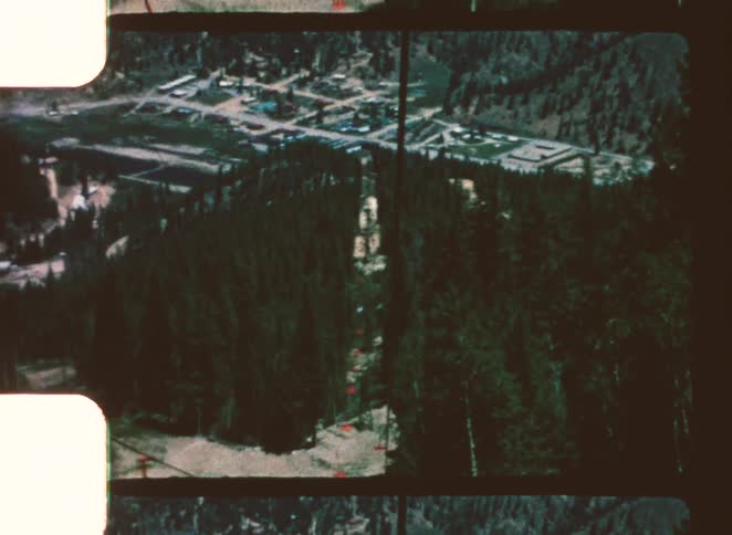 Red ski lift crosses forested mountain area during snowless season