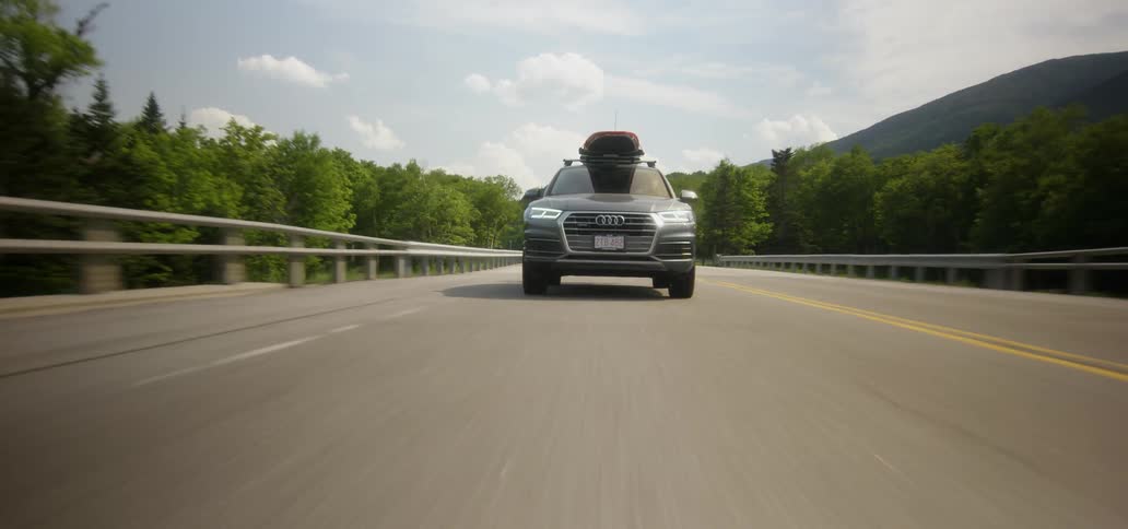 Car with surfboard on top driving down a highway on cloudy day