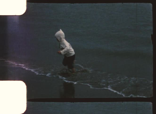 Child running along the shoreline with water hitting their feet