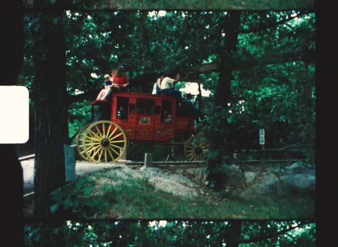 A group of people riding on a wagon pulled by horses
