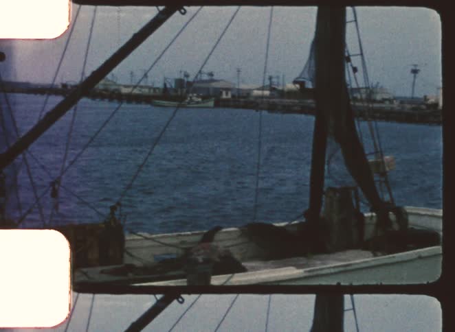 Two people walking on a wooden platform beside a docked vessel