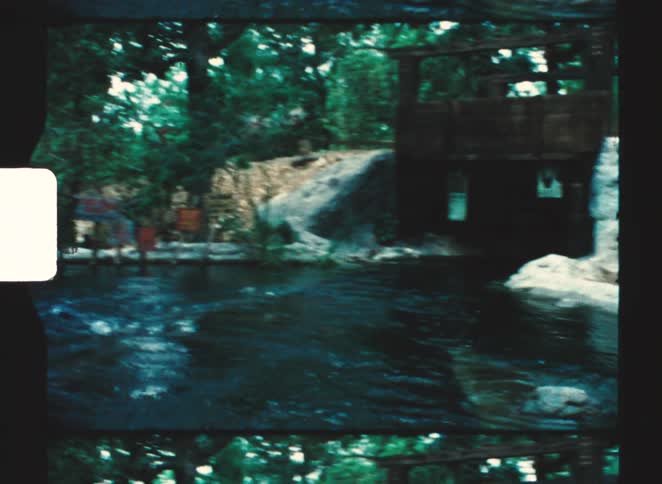 Stream flows through wooded area with wooden fence and visible signs