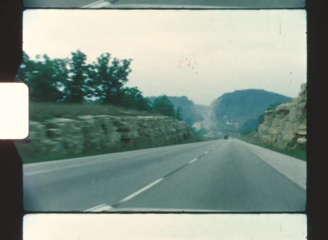 A road trip through the countryside at midday with a mountain range visible in the distance