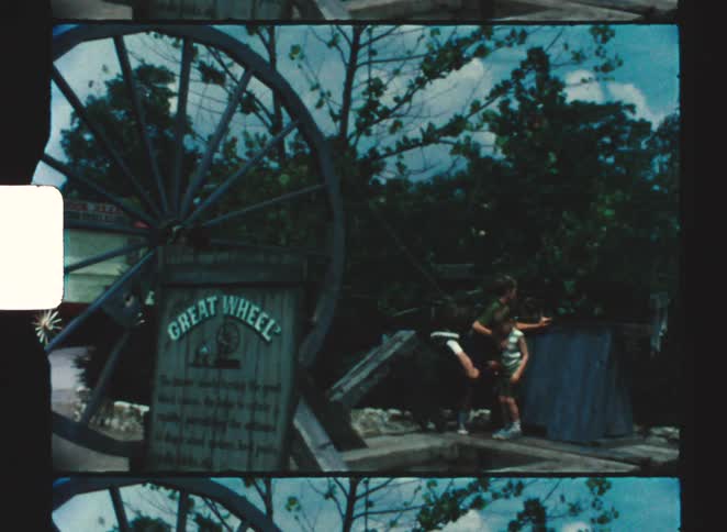 A couple kids checking out a tourist attraction of a giant wheel