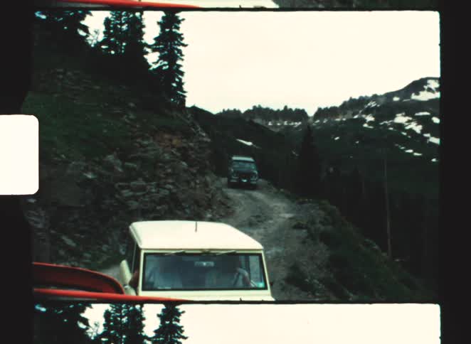 The vehicles drive on the trail on the large mountain range