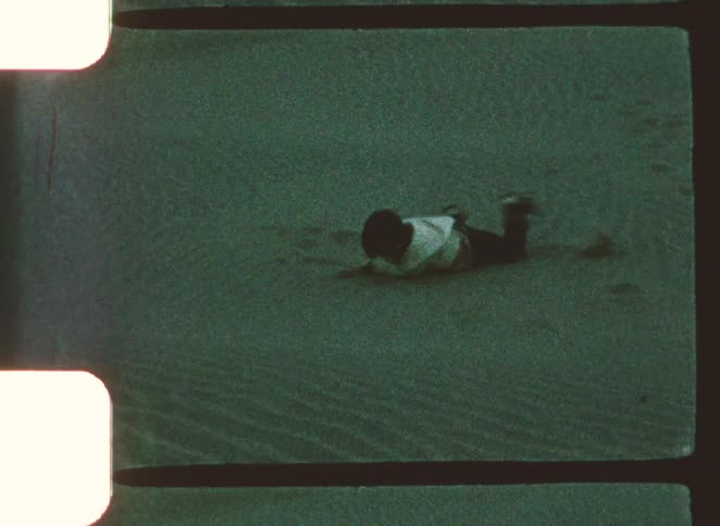 Child rolling on sand in a beach