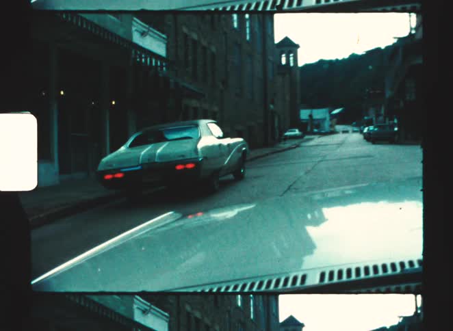 A drivers view is shown of a classic car driving down a hilly street in the dark vintage town of eureka springs