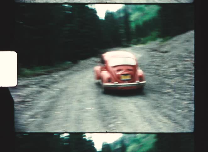 The car drives on the dirt road by the creek