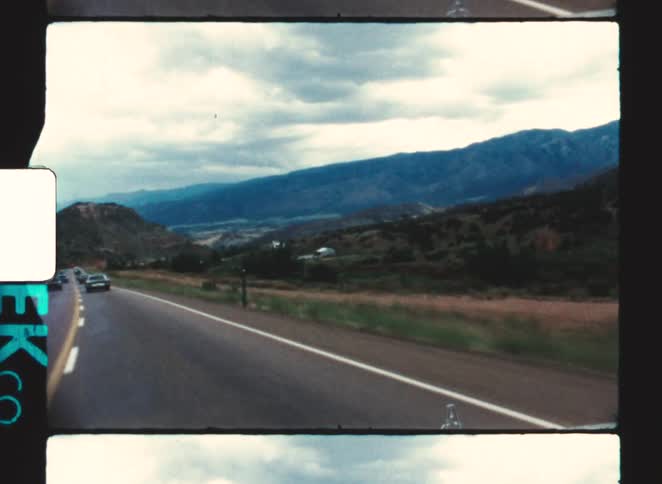 Traffic is flowing on the highway past the green mountains