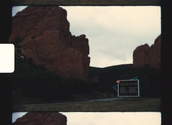 A sign by some large rocky outcroppings