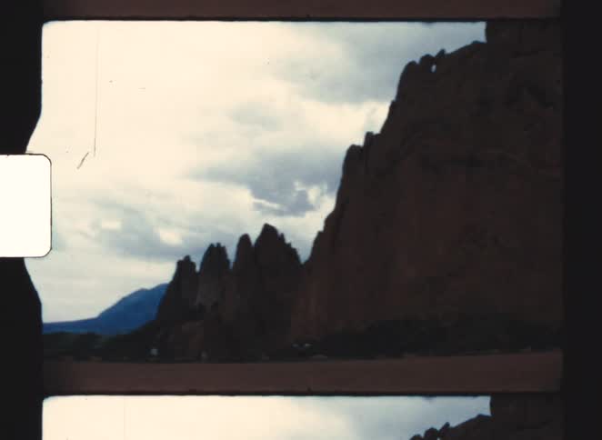 Captured from a moving vehicle the camera sweeps across a vast flat plain leading up to a rugged mountain range shrouded in thick lowhanging clouds